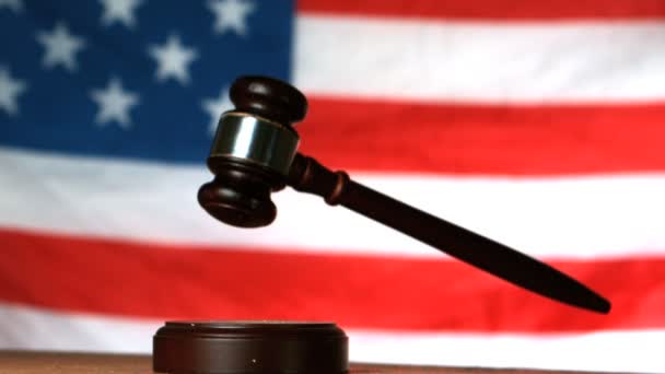 Gavel dropping on sounding block with american flag in background — Stock Video