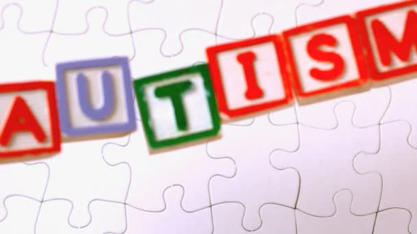 Autism blocks falling onto jigsaw surface — Stock Video