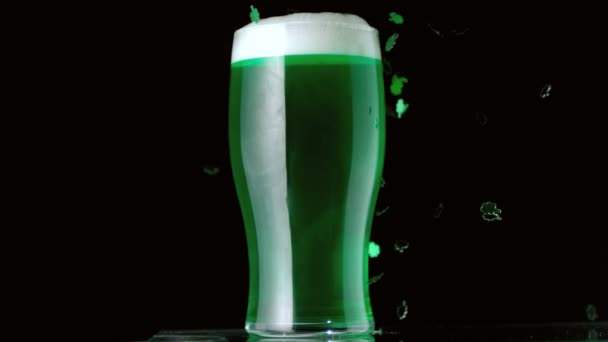 Shamrock confetti falling in front of pint of green beer — Stock Video