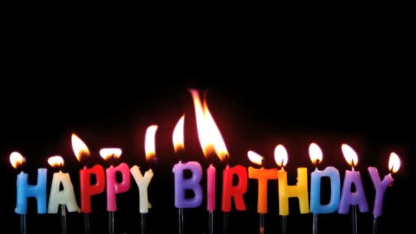 Colourful happy birthday candles being blown out with copy space on black background — Stock Video