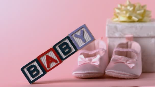 Baby blocks toppling over with booties and gift box in background — Stock Video