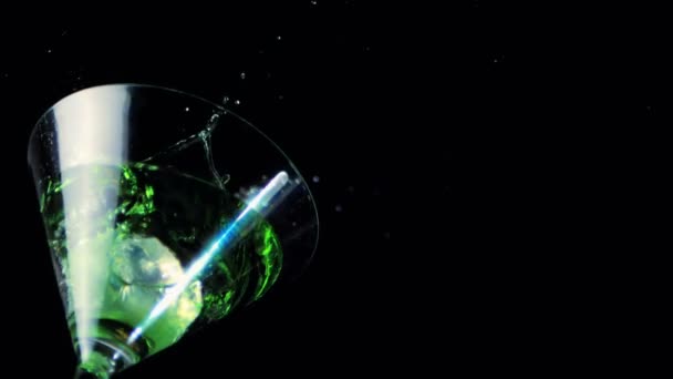 Ijs vallen in cocktailglas van groene vloeistof — Stockvideo