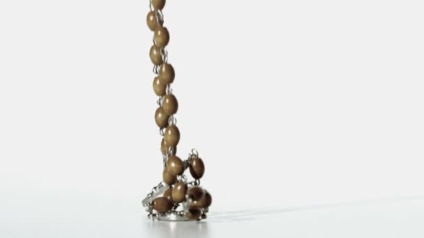 Rosary beads falling onto a white surface — Stock Video