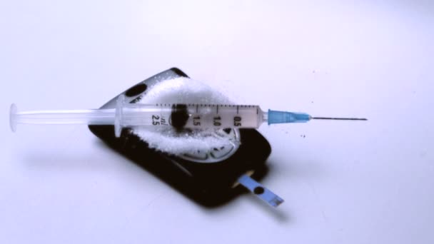 Syringe falling onto pile of sugar on blood glucose monitor — Stock Video