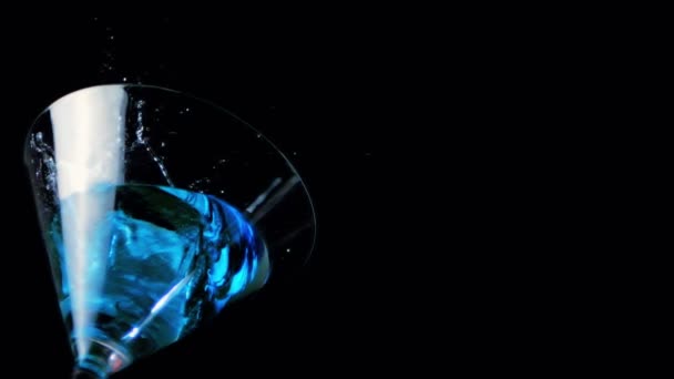Ice falling into cocktail glass of blue liquid — Stock Video