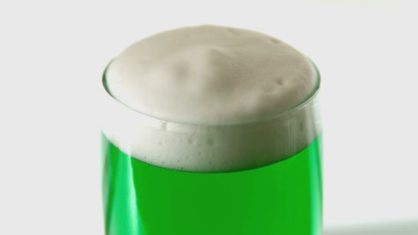 Shamrock confetti vallen op pint van groene bier in slow motion — Stockvideo