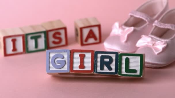 Es ist eine Mädchenbotschaft in Buchstabenblöcken neben rosa Booties — Stockvideo