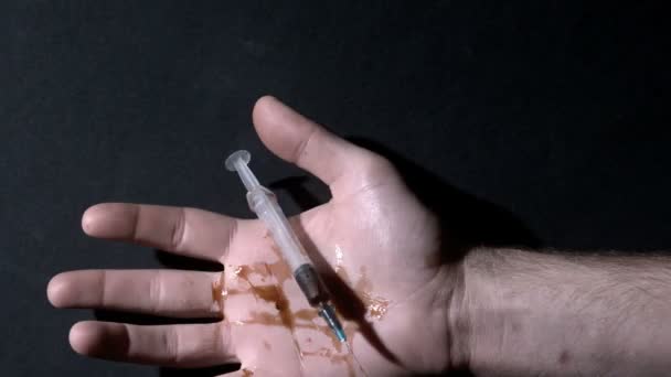 Рука держит протекающий шприц, падающий замертво — стоковое видео