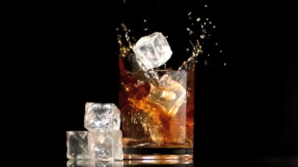 Cubos de hielo cayendo en un vaso de whisky y hielo — Vídeos de Stock