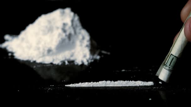 Ktoś parskanie linii kokainy obok duży stos — Wideo stockowe