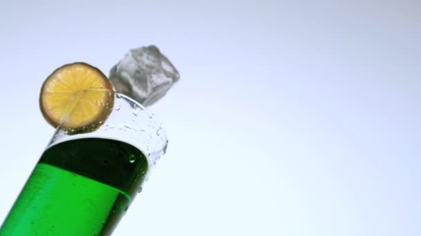 Лёд падает в стакан зеленого коктейля — стоковое видео