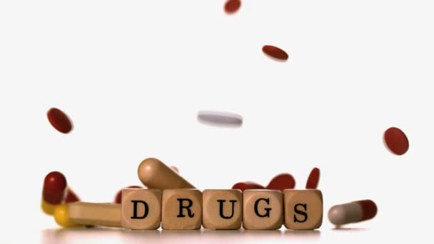 Verschillende tabletten gieten over dobbelstenen spelling drugs — Stockvideo