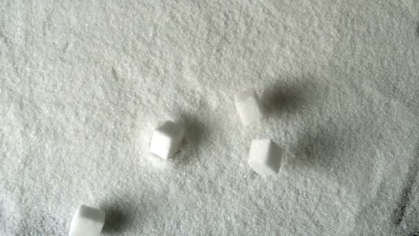 Five sugar cubes falling into pile of sugar — Stock Video