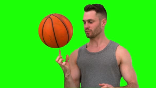 Man spinnen de basketbal aan zijn vinger op groene achtergrond — Stockvideo