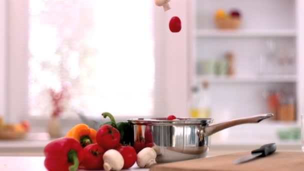 Cherry tomatoes and mushrooms falling in saucepan in kitchen — Stock Video