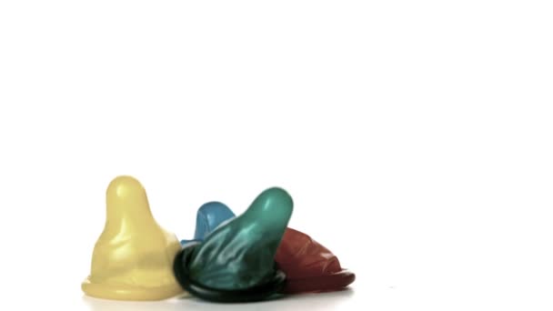 Четыре презерватива падают на белый фон — стоковое видео