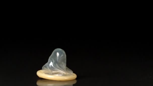 Condom falling over on black background — Stock Video