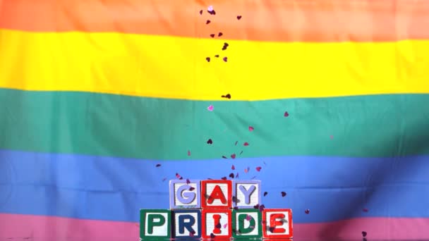 Arcobaleno bandiera in movimento nella brezza con gay orgoglio blocchi e coriandoli caduta — Video Stock