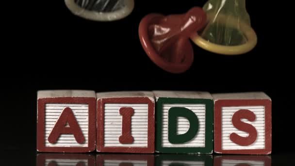 Gekleurde condooms vallen op blokken spelling aids — Stockvideo