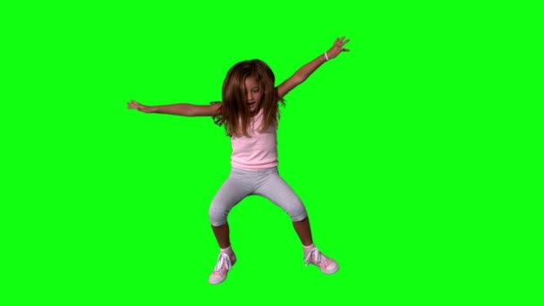 Cute little girl jumping with limbs outstretched on green screen — Stock Video