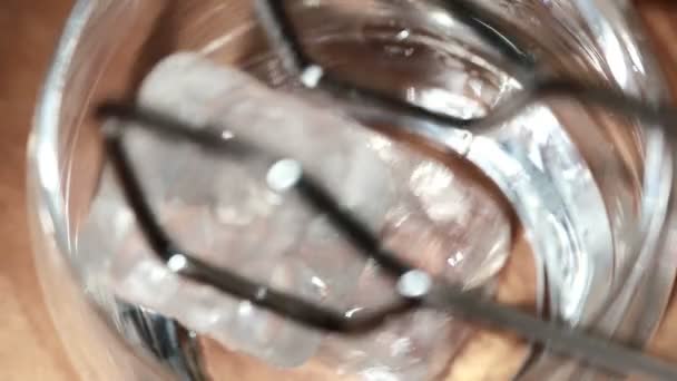 Tongs placing ice into tumbler and whiskey being poured over — Stock Video