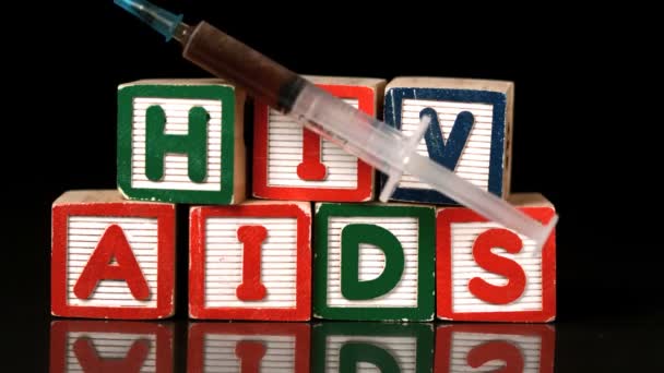 Syringe falling on wooden blocks spelling Aids and Hiv — Stock Video