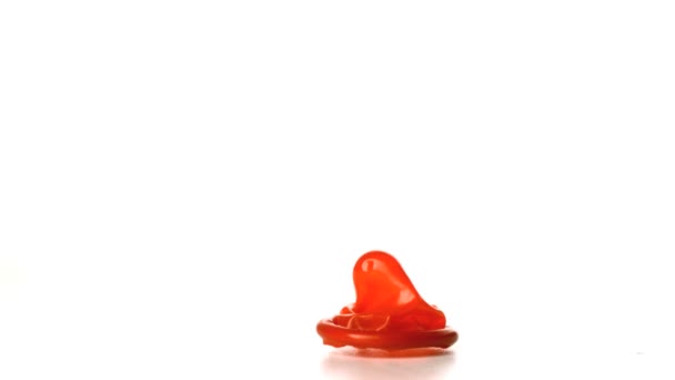 Red condom falling on white background — Stock Video