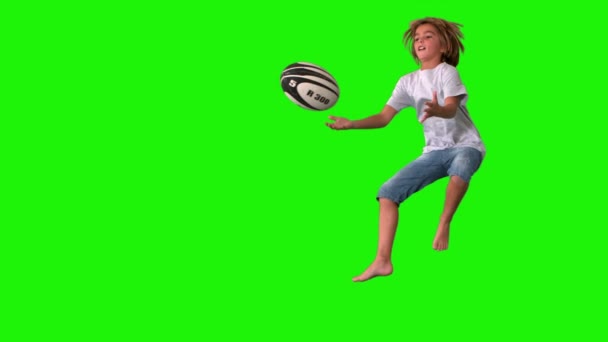 Menino pulando para pegar bola de rugby na tela verde — Vídeo de Stock