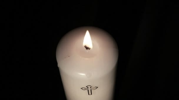 Candle with cross embellishment burning and being blown out — Stock Video