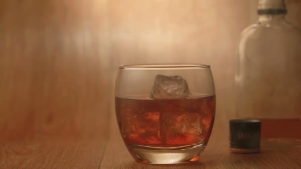 Cigar being smoked beside tumbler of whiskey on the rocks — Stock Video