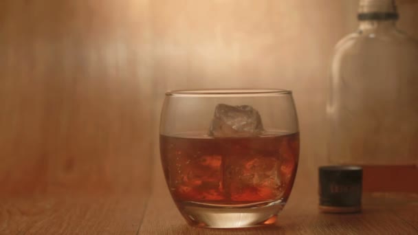 Cigarrillo que se fuma junto a vaso de whisky en las rocas — Vídeo de stock