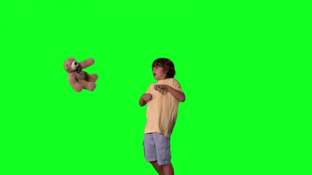 Little boy jumping up and kicking teddy on a green screen — Stock Video