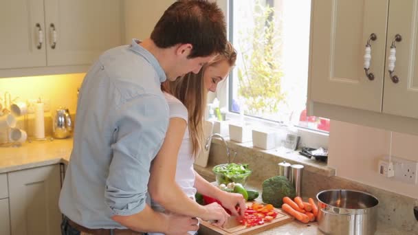 Женщина режет овощи с мужчиной, стоящим позади нее — стоковое видео