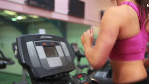 Spor salonunda koşu bandı üzerinde çalışan kadın — Stok video