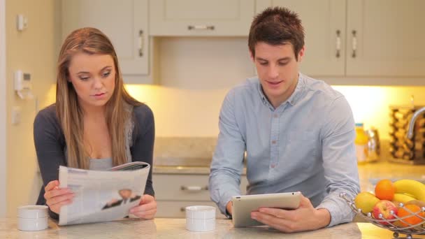 Mujer leyendo el periódico con el hombre sosteniendo una tableta PC — Vídeos de Stock