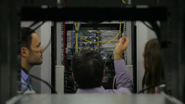 Two persons watching man while fixing wires — Stock Video