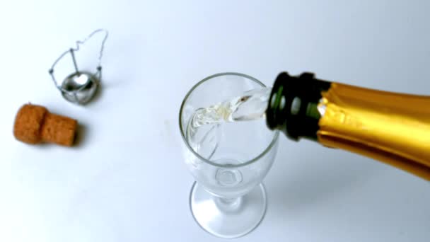 Champagne wordt gegoten in de fluit op witte oppervlakte hoge hoekmening — Stockvideo
