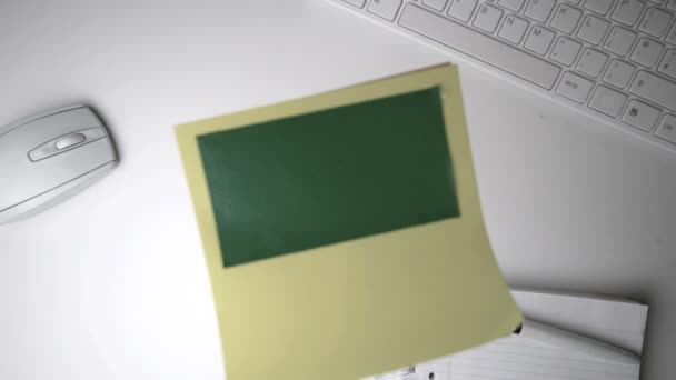 Yellow post it with green copy space falling on office desk — Stock Video