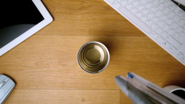 Pennor faller och landar i glas på skrivbord — Stockvideo