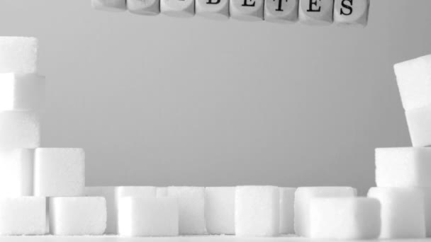 Dice spelling out diabetes falling over sugar cubes in black and white — Stock Video