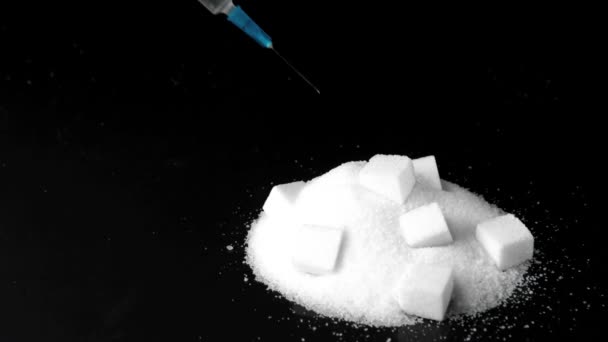 Syringe of insulin falling into pile of sugar with sugar cubes in it — Stock Video