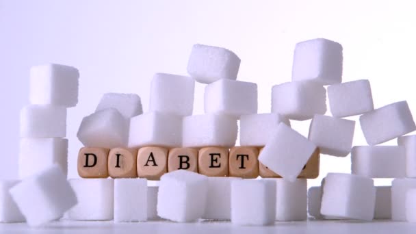 Sugar cubes falling in front of wood dice spelling out diabetes — Stock Video