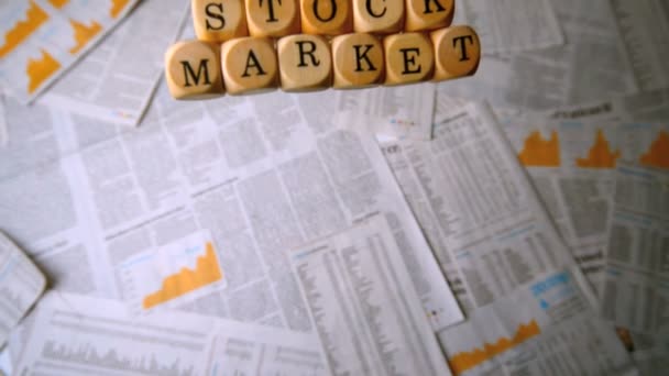 Dados de madeira soletrando mercado de ações caindo sobre folhas de papel — Vídeo de Stock