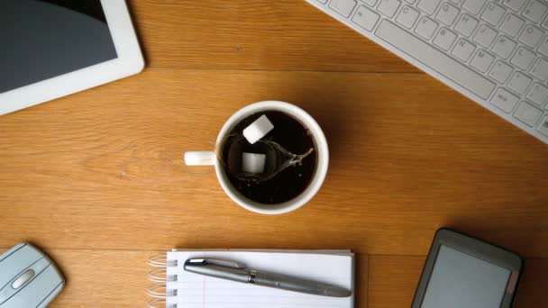 Sugar cubes falling into cup of coffee and splashing a tablet pc — Stock Video