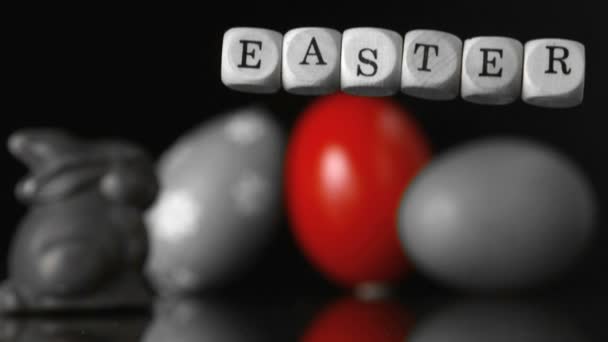 Tärningar stava ut påsk faller framför påsk fester och ägg svart och vitt — Stockvideo