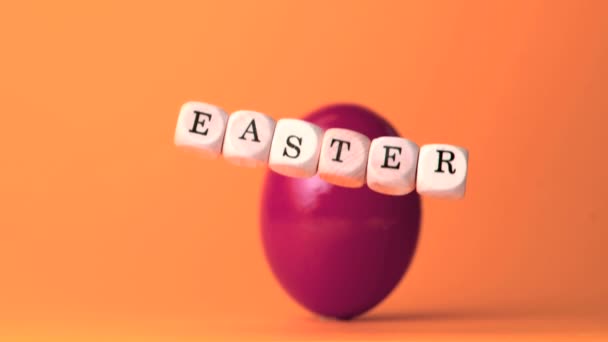 Dobbelstenen spelling uit Pasen vallen tegen oranje achtergrond — Stockvideo