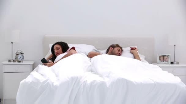 Woman texting while her partner is sleeping — Stock Video