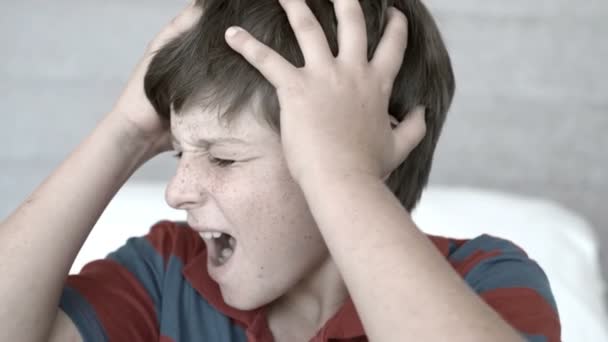 Annoyed boy holding his head between hands — Stock Video