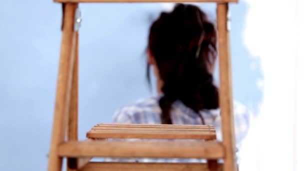 Atractiva mujer saltando para pintar su pared y luego descansando — Vídeo de stock