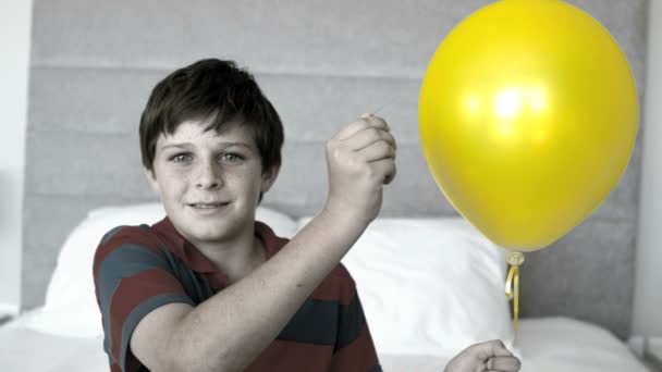 Boy piercing his balloon in the bedroom in selective color — Stock Video